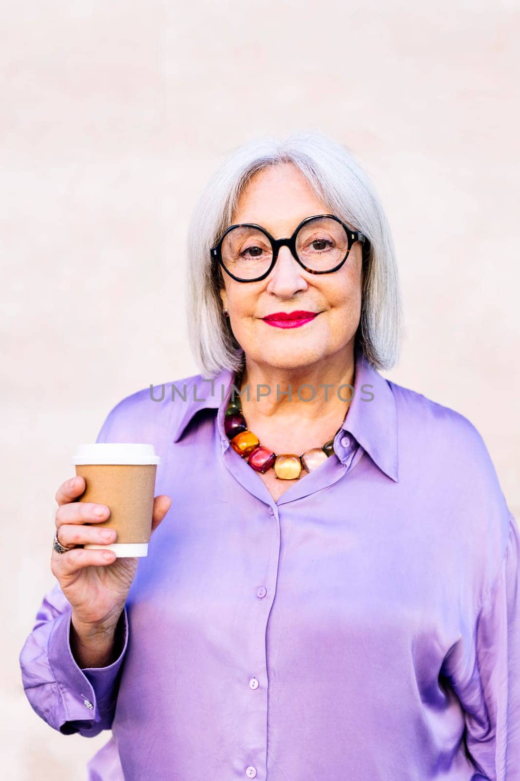 smiling senior woman holding a takeaway coffee by raulmelldo