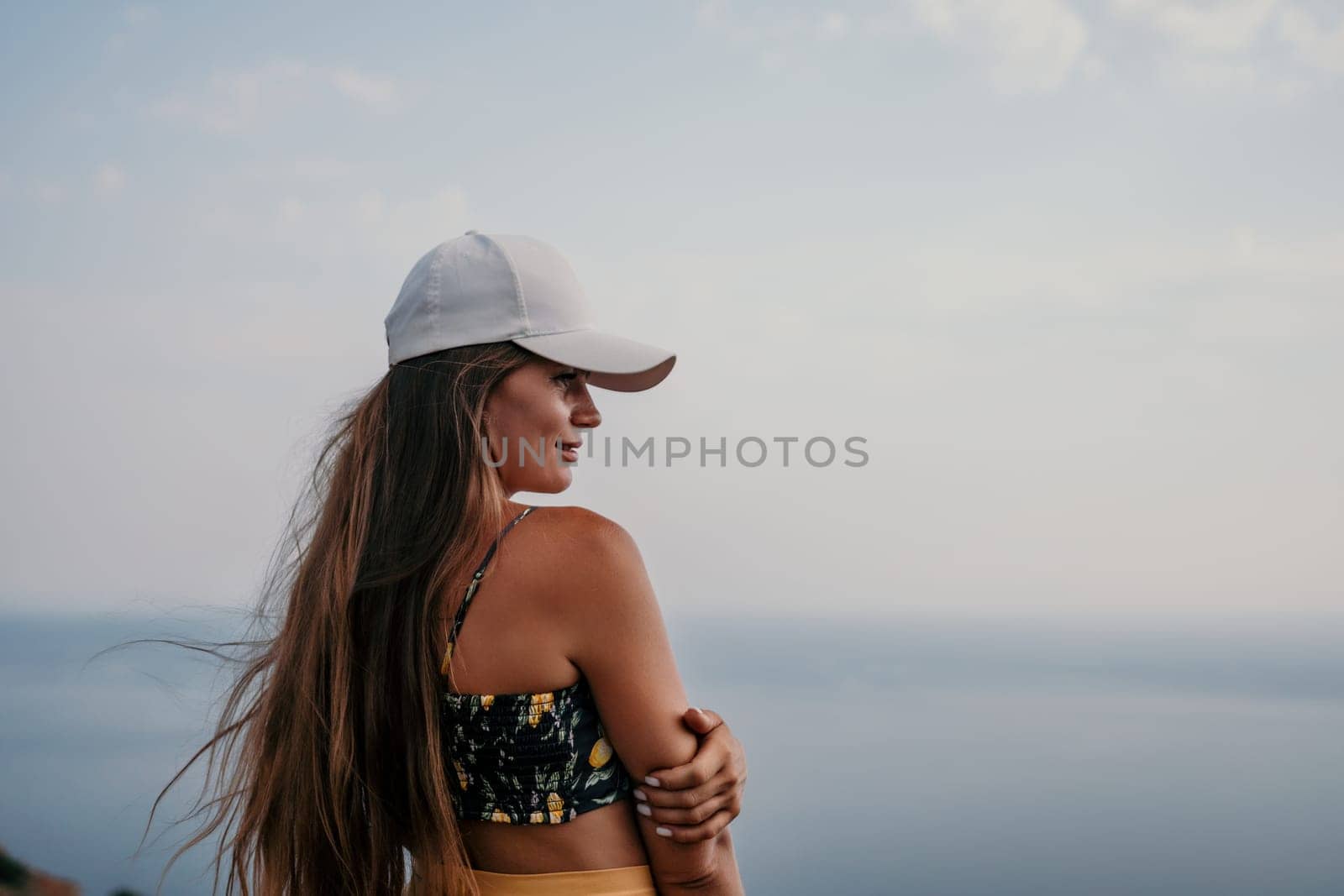 Woman travel sea. Happy tourist taking picture outdoors for memories. Woman traveler looks at the edge of the cliff on the sea bay of mountains, sharing travel adventure journey.