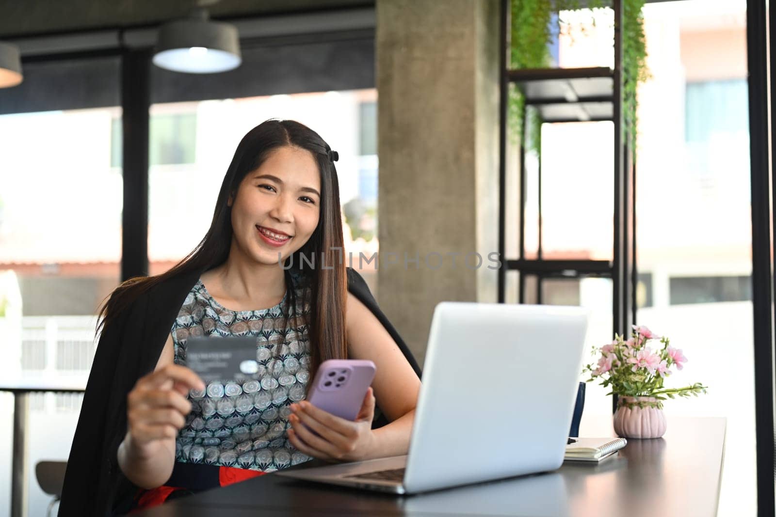 Millennial businesswoman holding mobile phone and credit card. Banking transaction and shopping online concept.