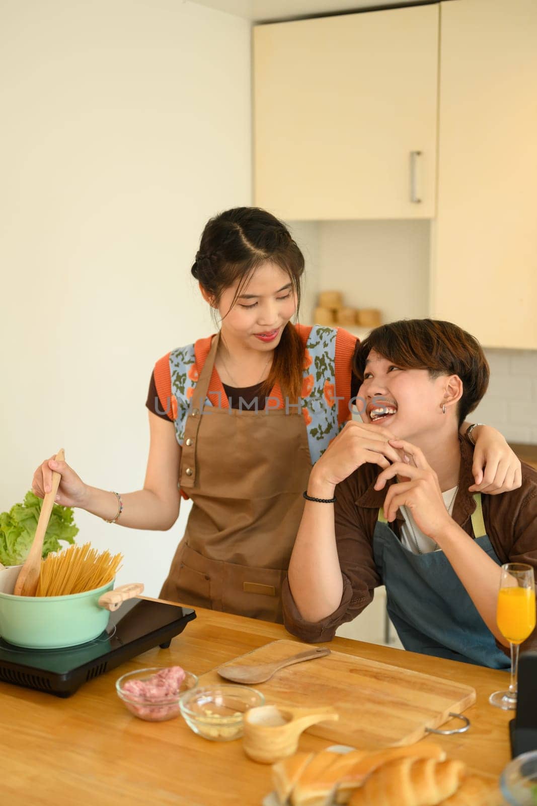 Cheerful young couple having fun cooking in the kitchen at home on weekend.