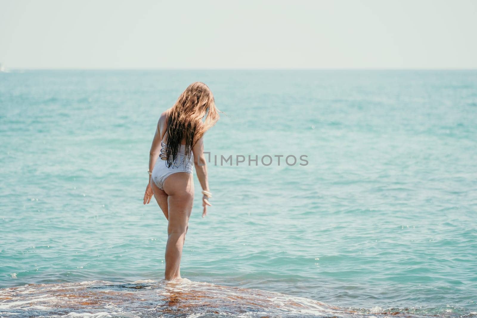 Woman sea yoga. Back view of free calm happy satisfied woman with long hair standing on top rock with yoga position against of sky by the sea. Healthy lifestyle outdoors in nature, fitness concept by panophotograph