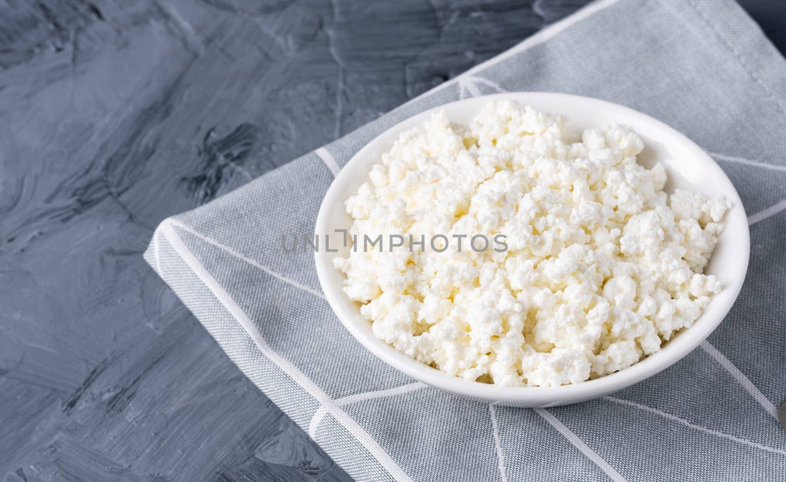 Cottage cheese in a white bowl on a grey background.