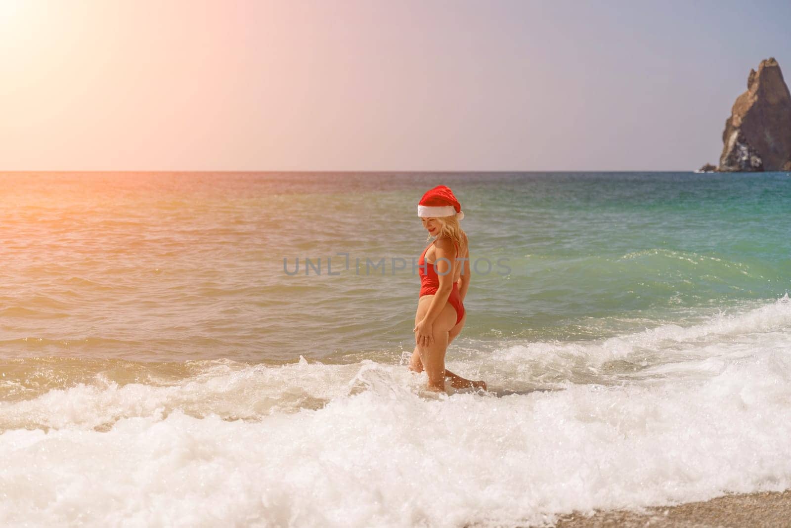 A woman in Santa hat on the seashore, dressed in a red swimsuit. New Year's celebration in a hot country by Matiunina