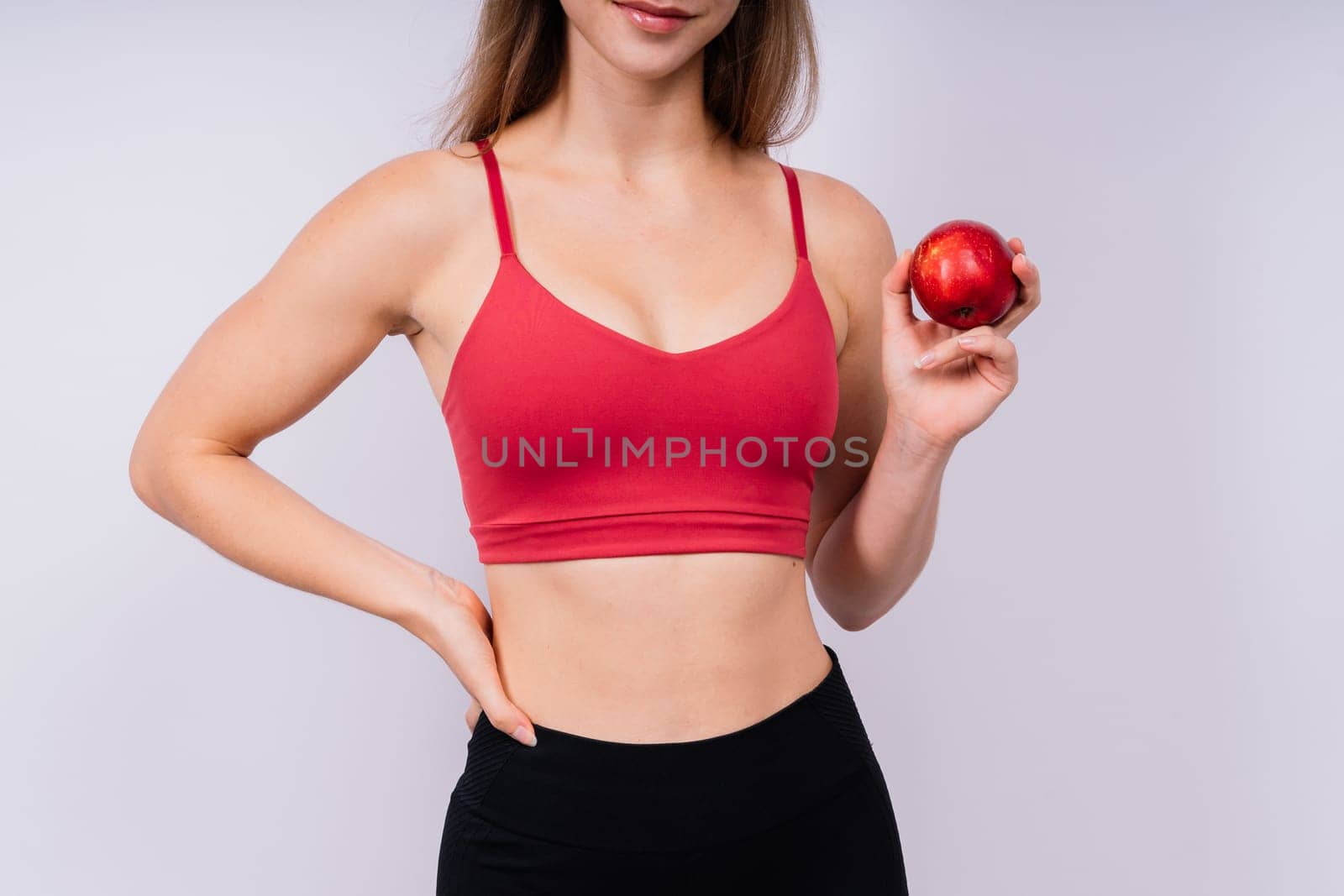 Cropped of sporty female with well fit body holding apple, healthy food and fit body concept by Zelenin