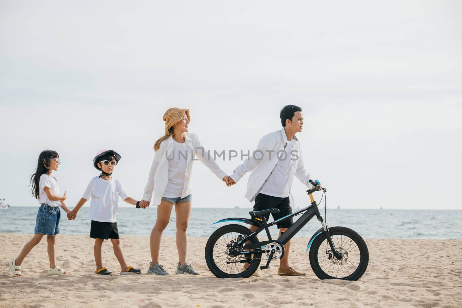 A family walk on the sandy beach parents pushing bicycles full of happiness joy and the carefree spirit of a childhood day by the sea. Family on beach vacation