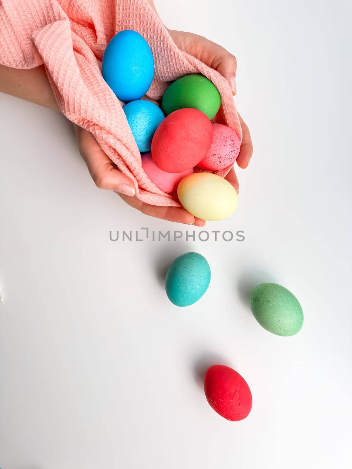 Hands cradling collection of brightly colored Easter eggs in pink fabric, evoking themes of Easter traditions, family fun, and springtime crafts. by Lunnica