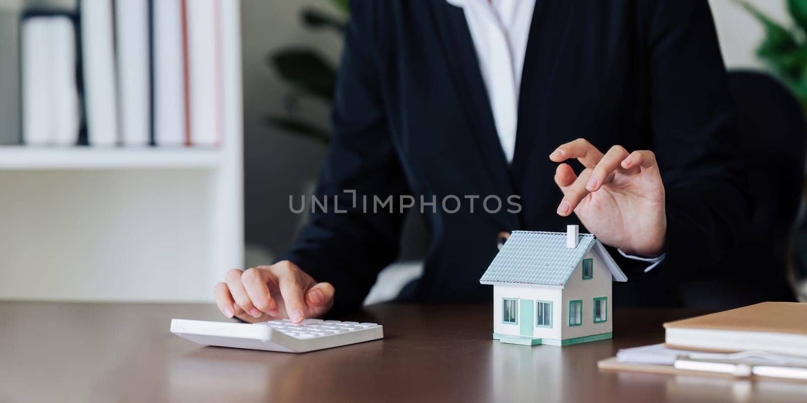 Agent worker are using calculator to calculate home loan interest rates for customers by itchaznong