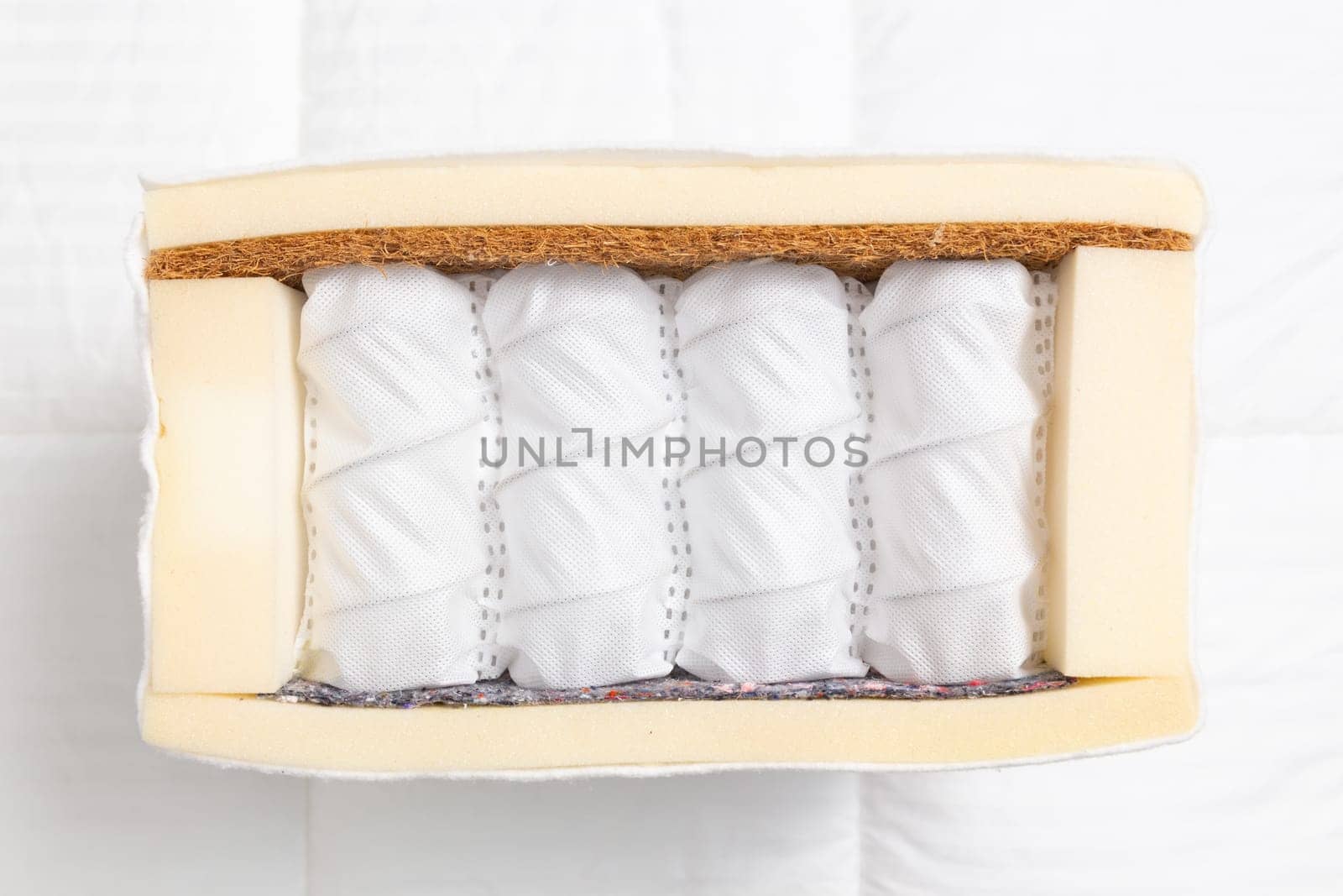 Sample of modern orthopedic mattress on textile. Mattress in section with springs on white background. Part of the mattress for familiarization with the materials.