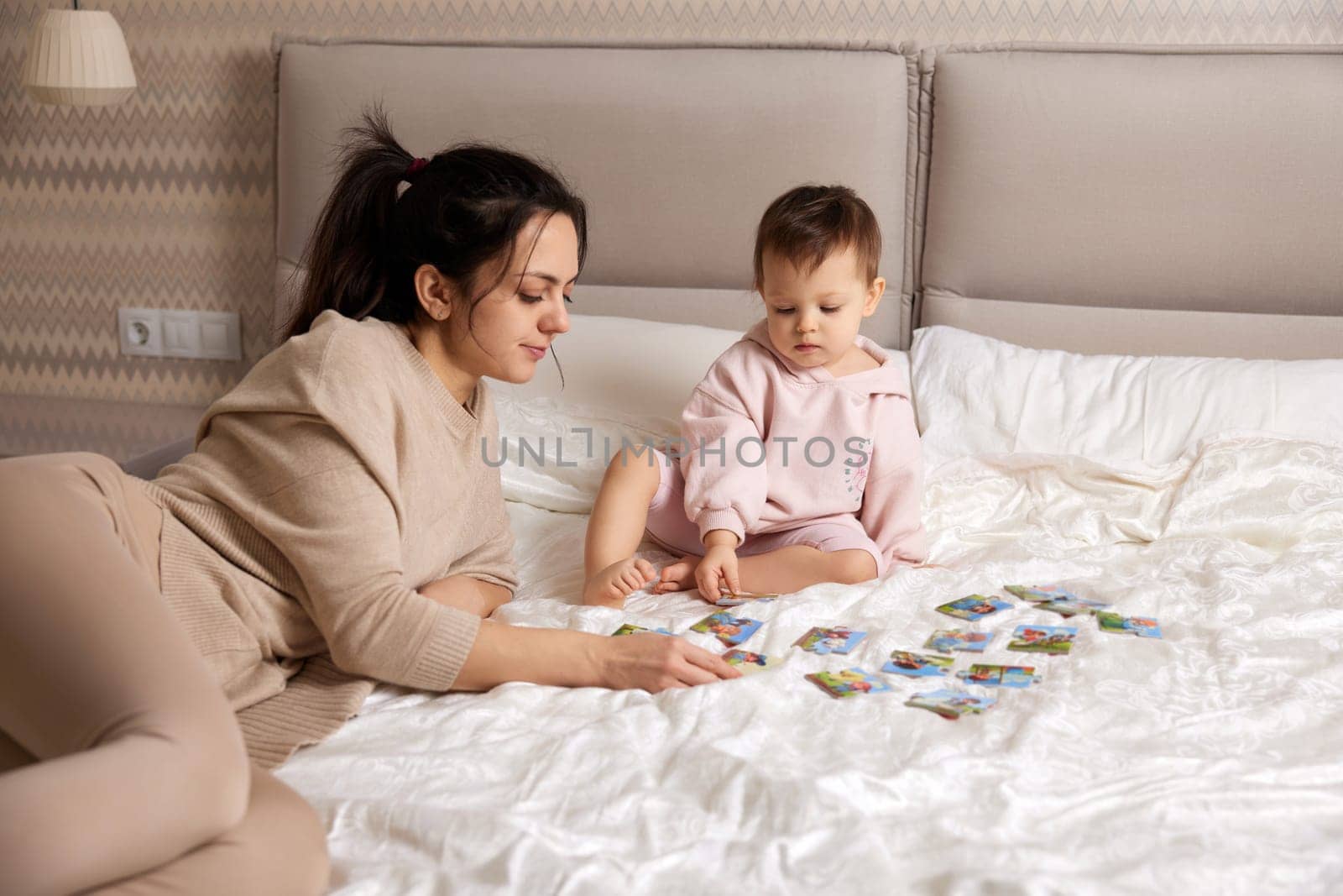 mother playing puzzle with her little child girl by erstudio
