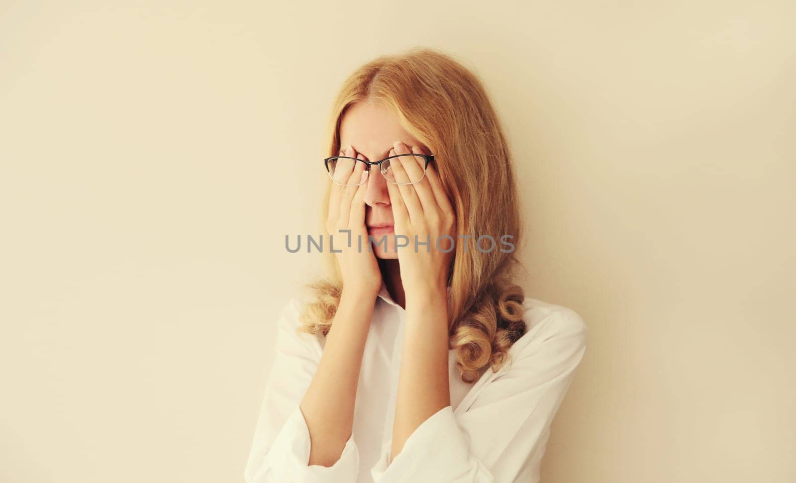Tired overworked young woman employee rubbing her eyes suffering from eye strain or headaches after working at computer. Exhausted office worker