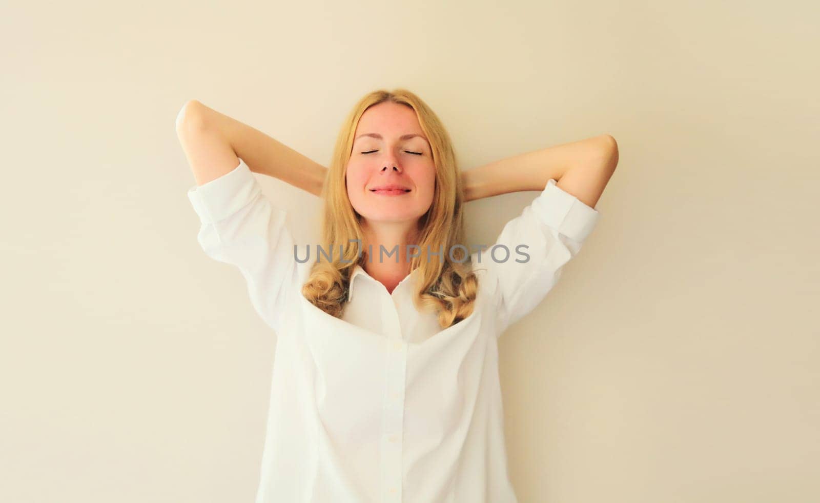 Relaxed happy young woman take a break meditates with closed eyes and folded hands behind the head while working at home or office