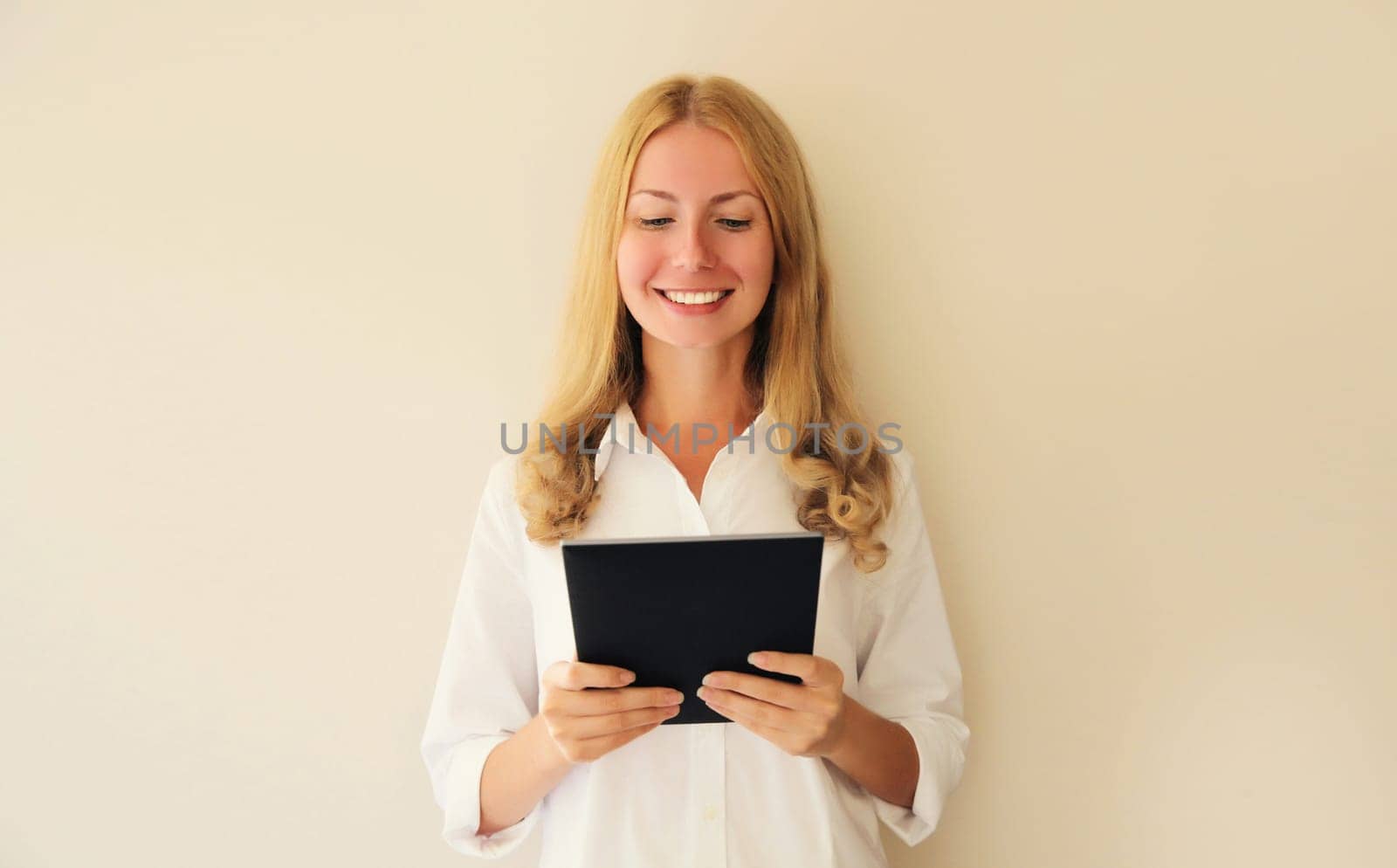 Portrait of happy smiling caucasian young woman employee with digital tablet computer or folder with documents in office