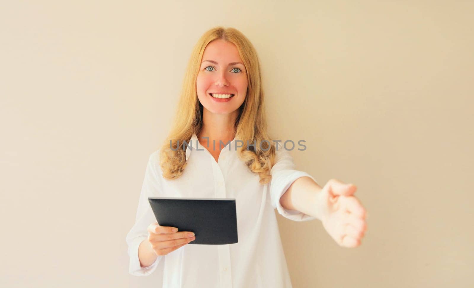 Happy smiling woman employer stretches out her hand for handshake greets applicant holds digital tablet computer in office
