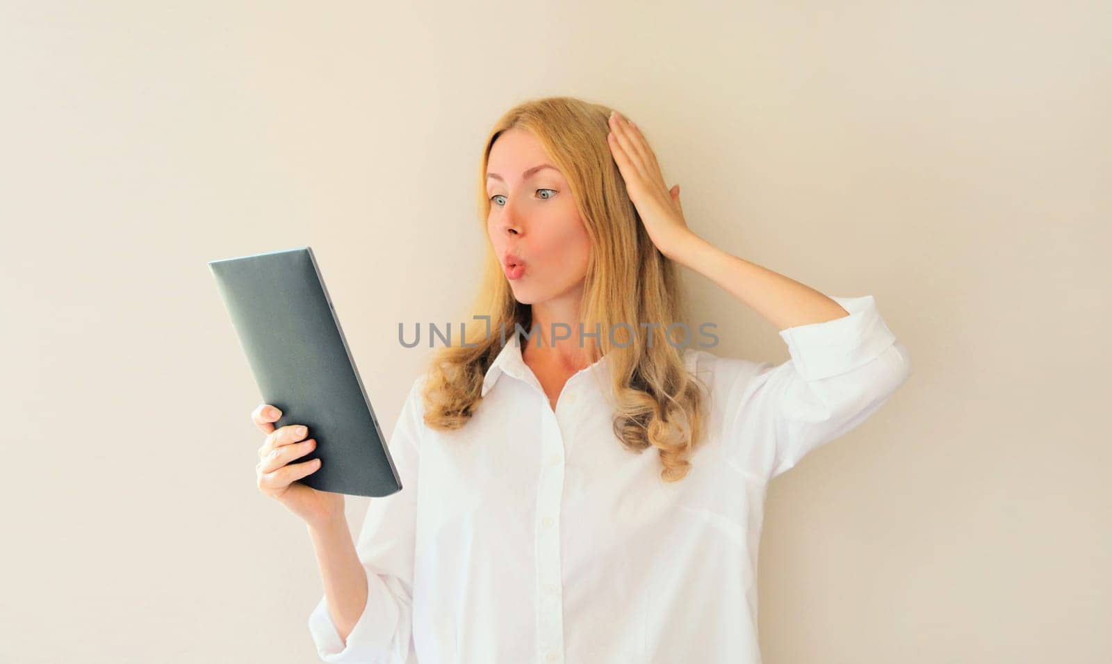 shocked and surprised caucasian young woman employee looking at digital tablet computer or folder with documents, emotional overworked office manager