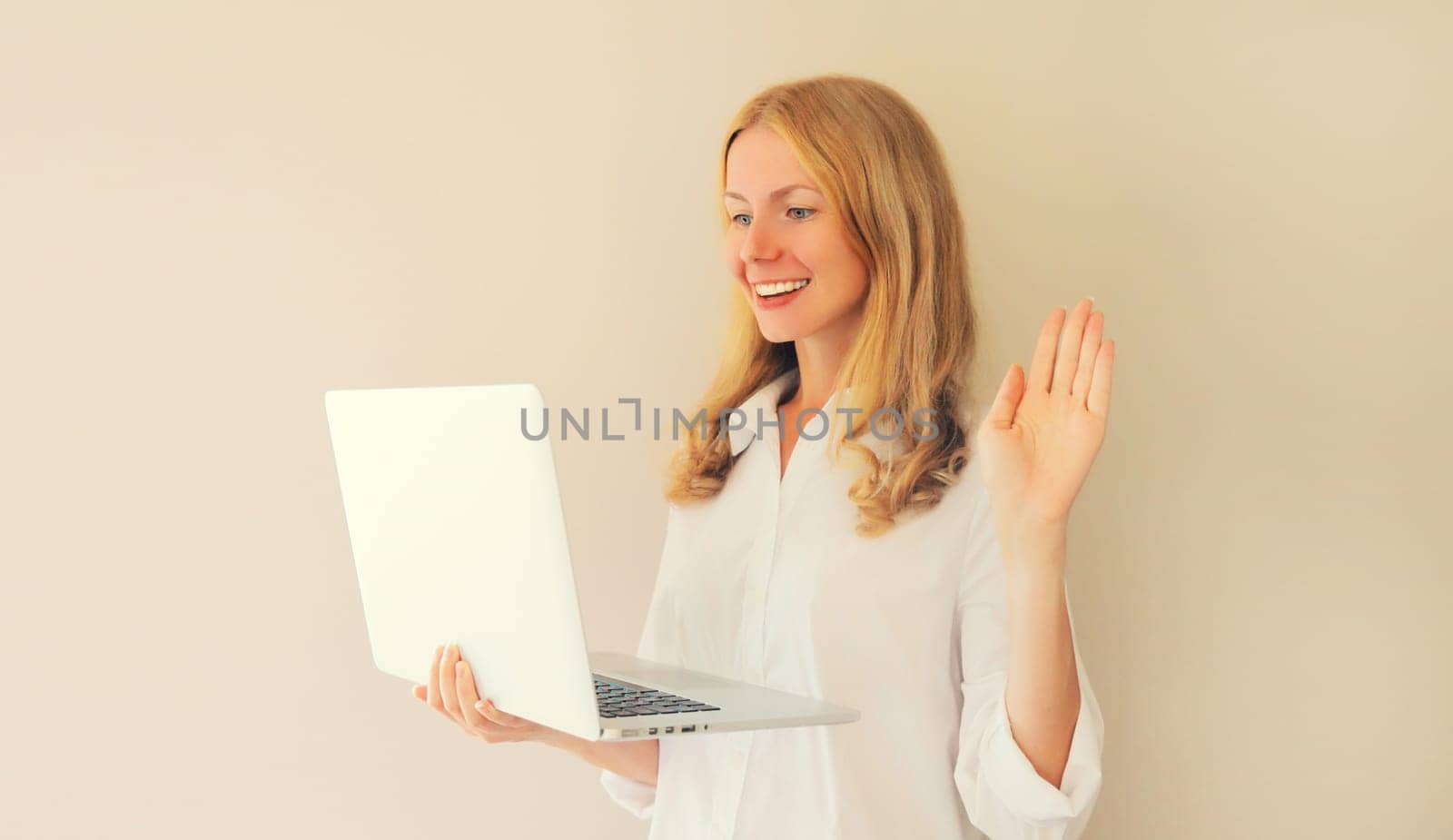 Happy smiling caucasian young woman greets communicates with friends via video call on laptop at home