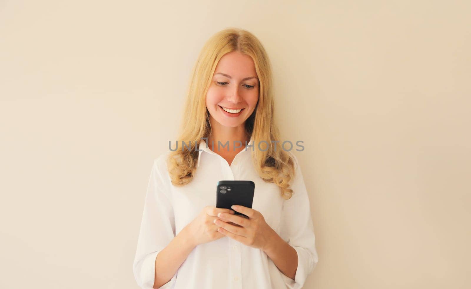 Portrait of happy smiling caucasian young woman 20s with mobile phone looking at device by Rohappy