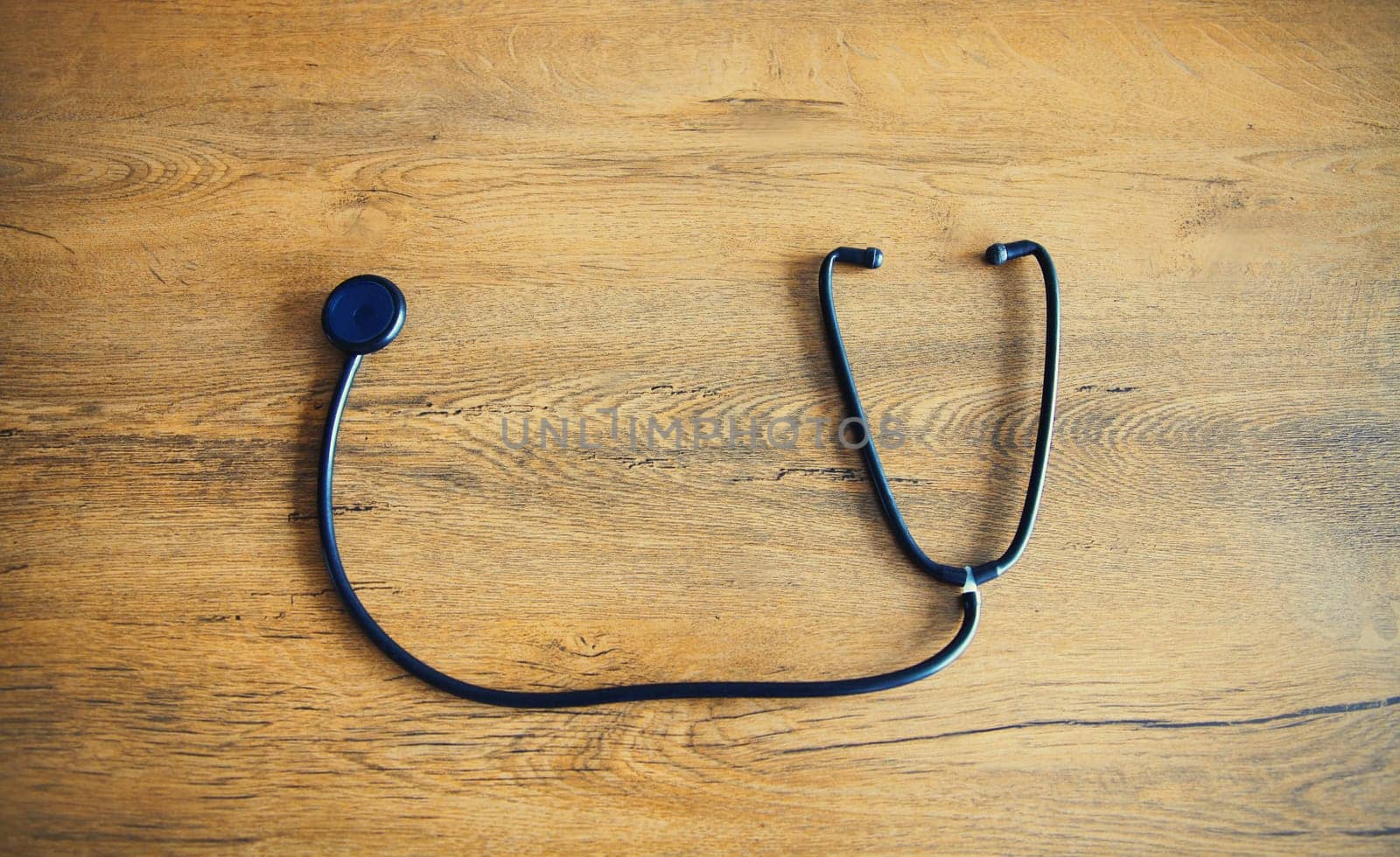 Close up medical stethoscope on wooden table, top view
