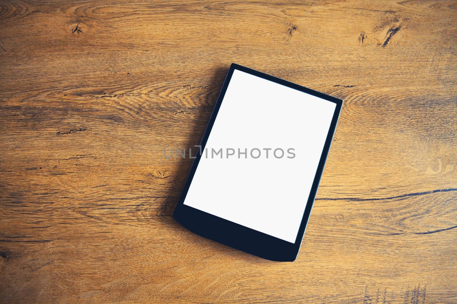 White blank screen digital tablet computer on wooden table at home, top view