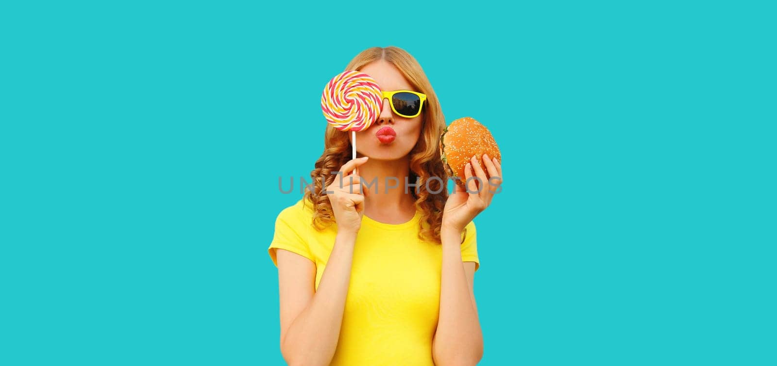 Portrait of happy cheerful young woman with burger fast food and sweet lollipop by Rohappy