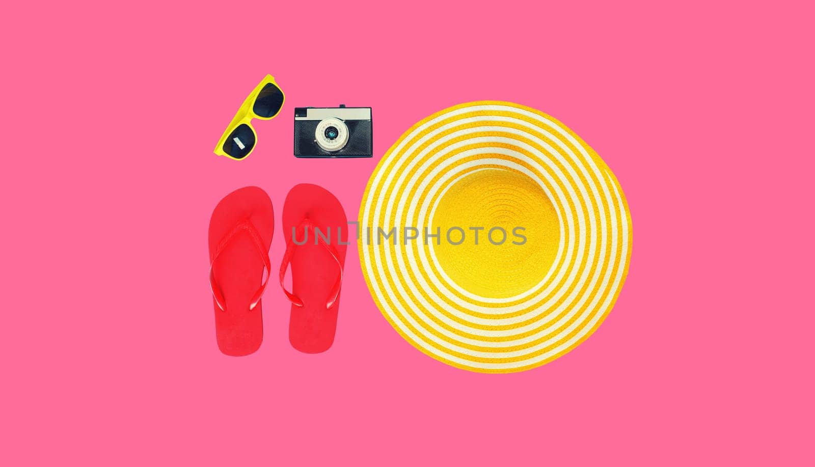 Summer vacation, yellow straw beach hat with flip flops, film camera and sunglasses on colorful pink background, top view