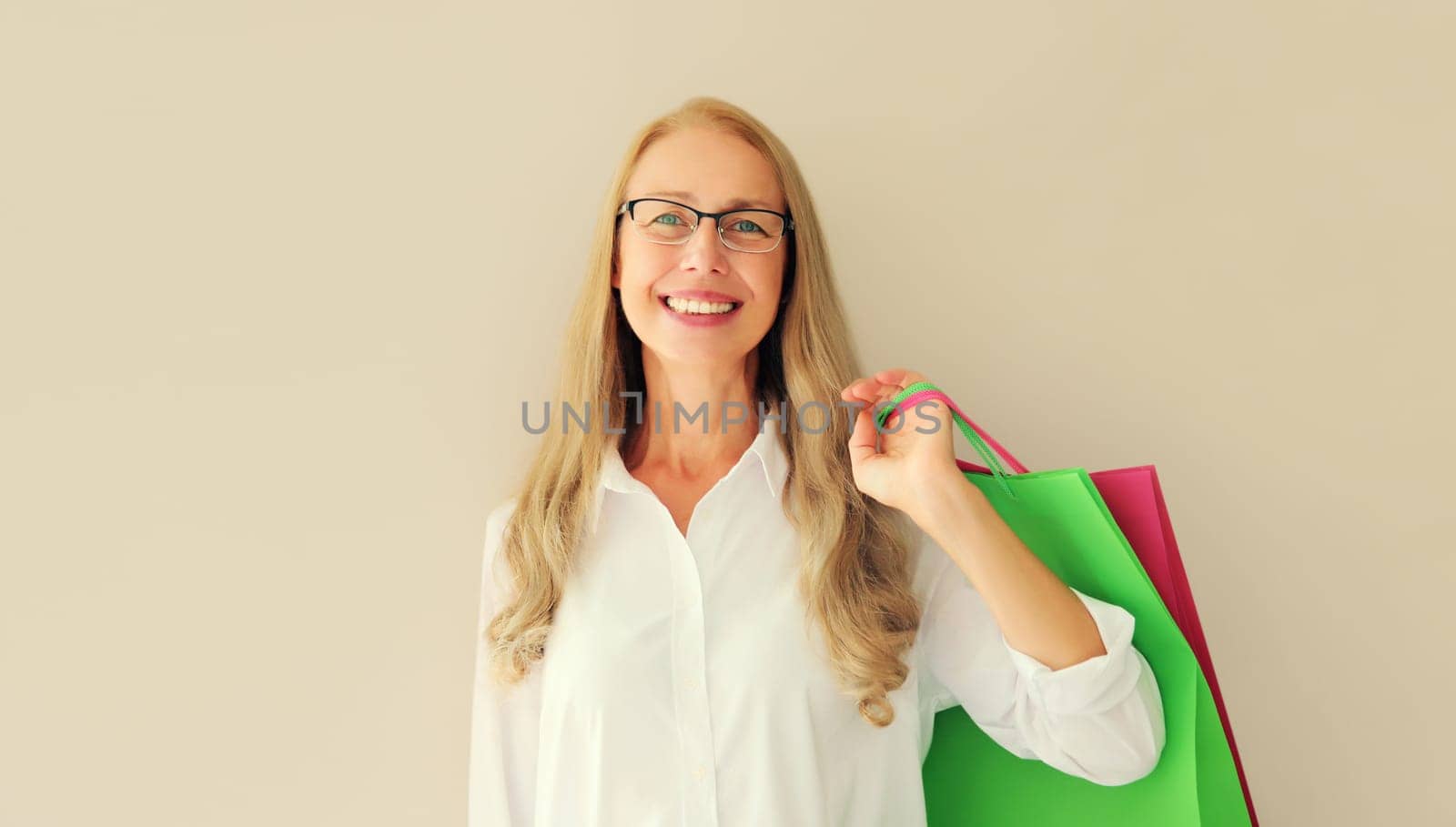 Portrait of beautiful happy smiling middle aged woman posing with shopping bags in eyeglasses by Rohappy