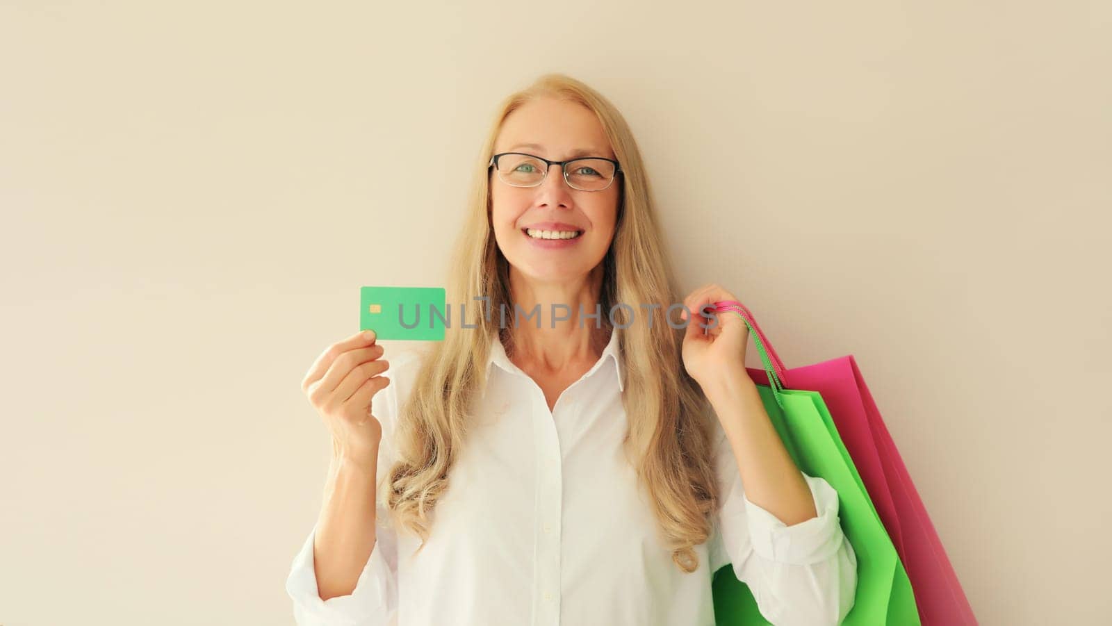 Portrait of happy smiling middle aged woman holding plastic credit bank card with shopping bags by Rohappy