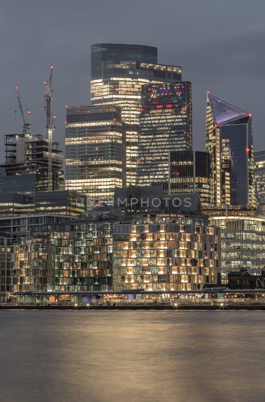 London, UK - Feb 15, 2024 - The illuminated of skyscraper in the business district of London with reflections in the River Thames just after sunset. View of architectural modern buildings of the city, Space for text, Selective Focus.