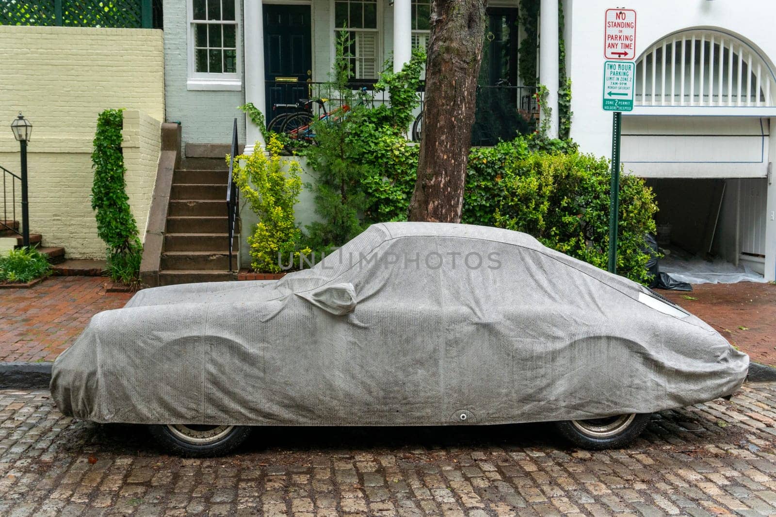 car covered by tarpaulin in the street by AndreaIzzotti