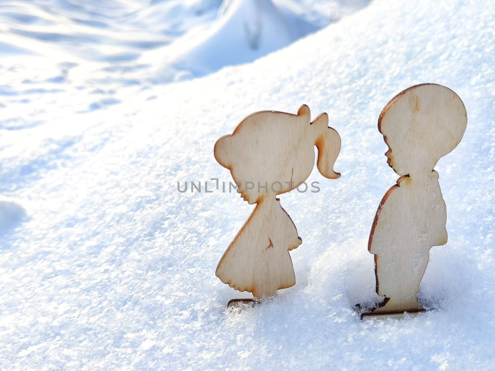 Wooden toys of boy and girl on white snow. Couple in love on Valentine's Day in February. Love in cold world. Card, background