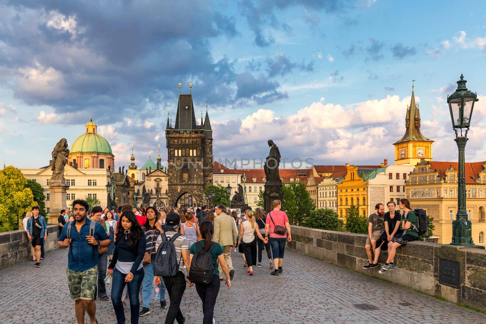 Prague, Czechia - 25 May 2018: People are walking over the famous Charles Bridge in Prague during sunny day.  View of the Lesser Bridge Tower of Charles Bridge (Karluv Most) full of tourists.
