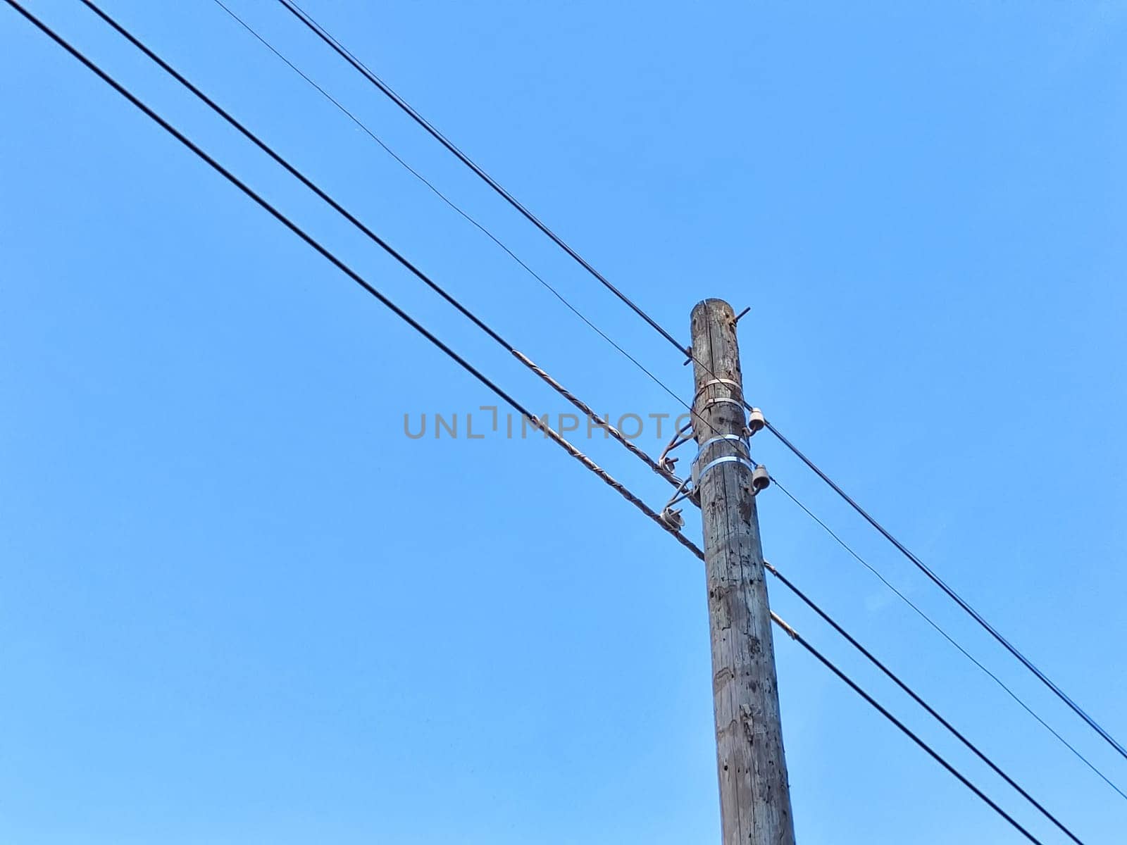 Old power line pole against blue sky in a nice sunny day