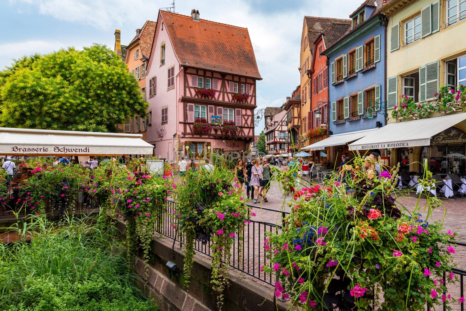 Colmar, France - July 27, 2018: Old town of Colmar, Alsace, France. View with colorful buildings, canal and flowers. Colmar, France. Petite Venice, water canal and traditional half timbered houses.