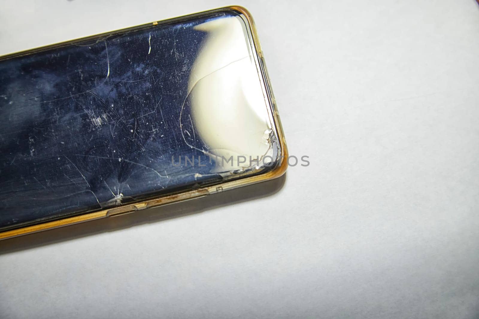 Close-Up View of a Cracked Smartphone Screen Against White Background. the detailed texture of a shattered smartphone screen, emphasizing extensive damage to the device
