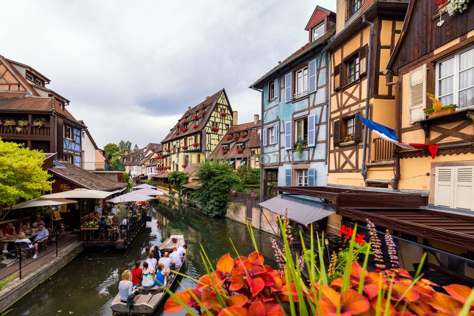 Colmar, France - July 27, 2018: Old town of Colmar, Alsace, France. View with colorful buildings, canal and flowers. Colmar, France. Petite Venice, water canal and traditional half timbered houses.