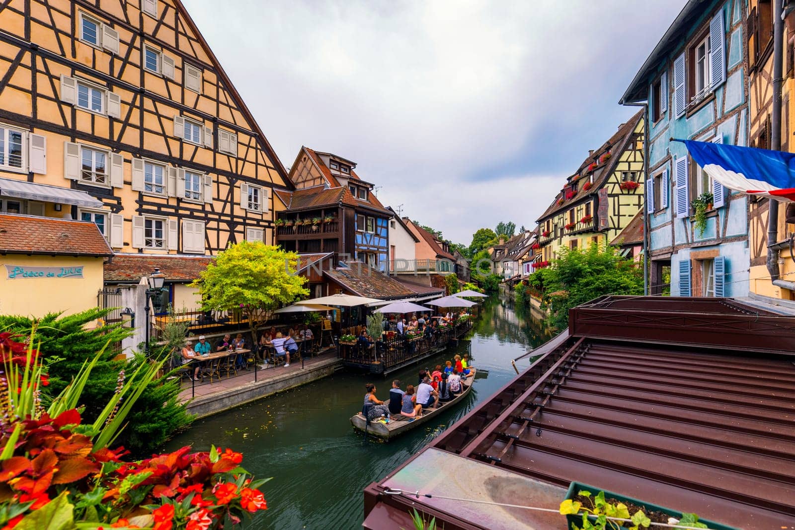 Colmar, France - July 27, 2018: Old town of Colmar, Alsace, France. View with colorful buildings, canal and flowers. Colmar, France. Petite Venice, water canal and traditional half timbered houses.