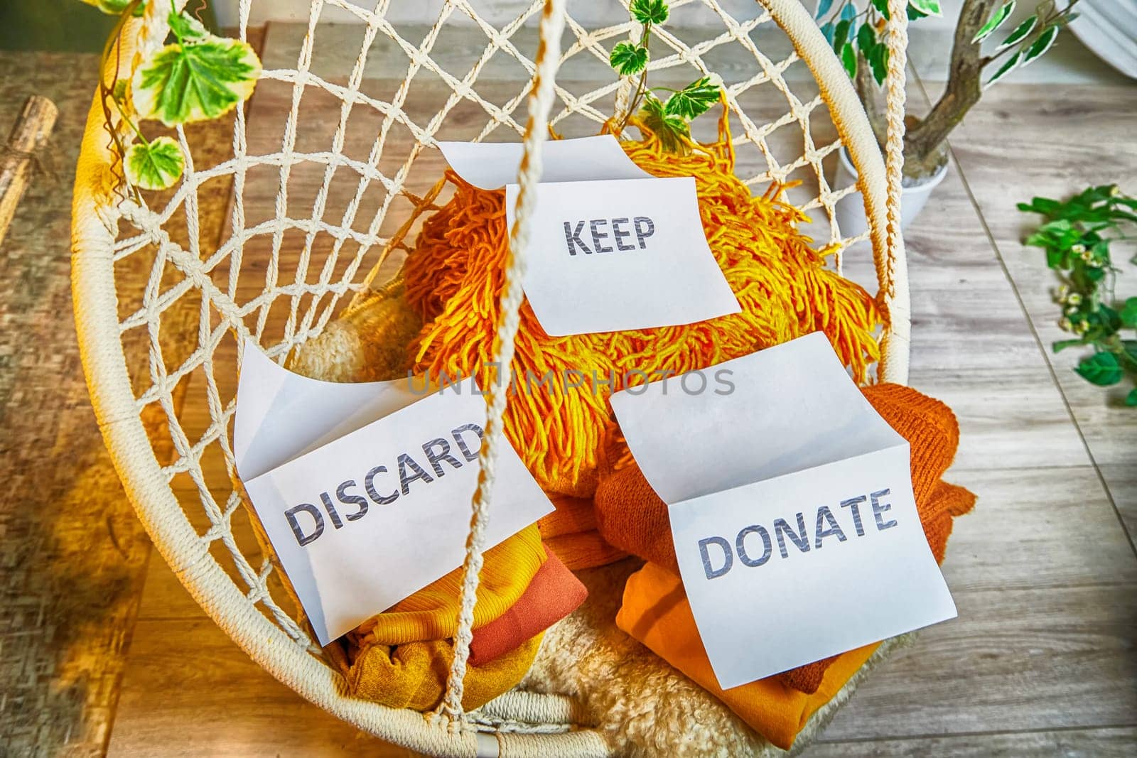 Signs with the words keep, donate, discard and fashion clothes folded in stacks in cozy room. The concept of cluttering and decluttering. Background