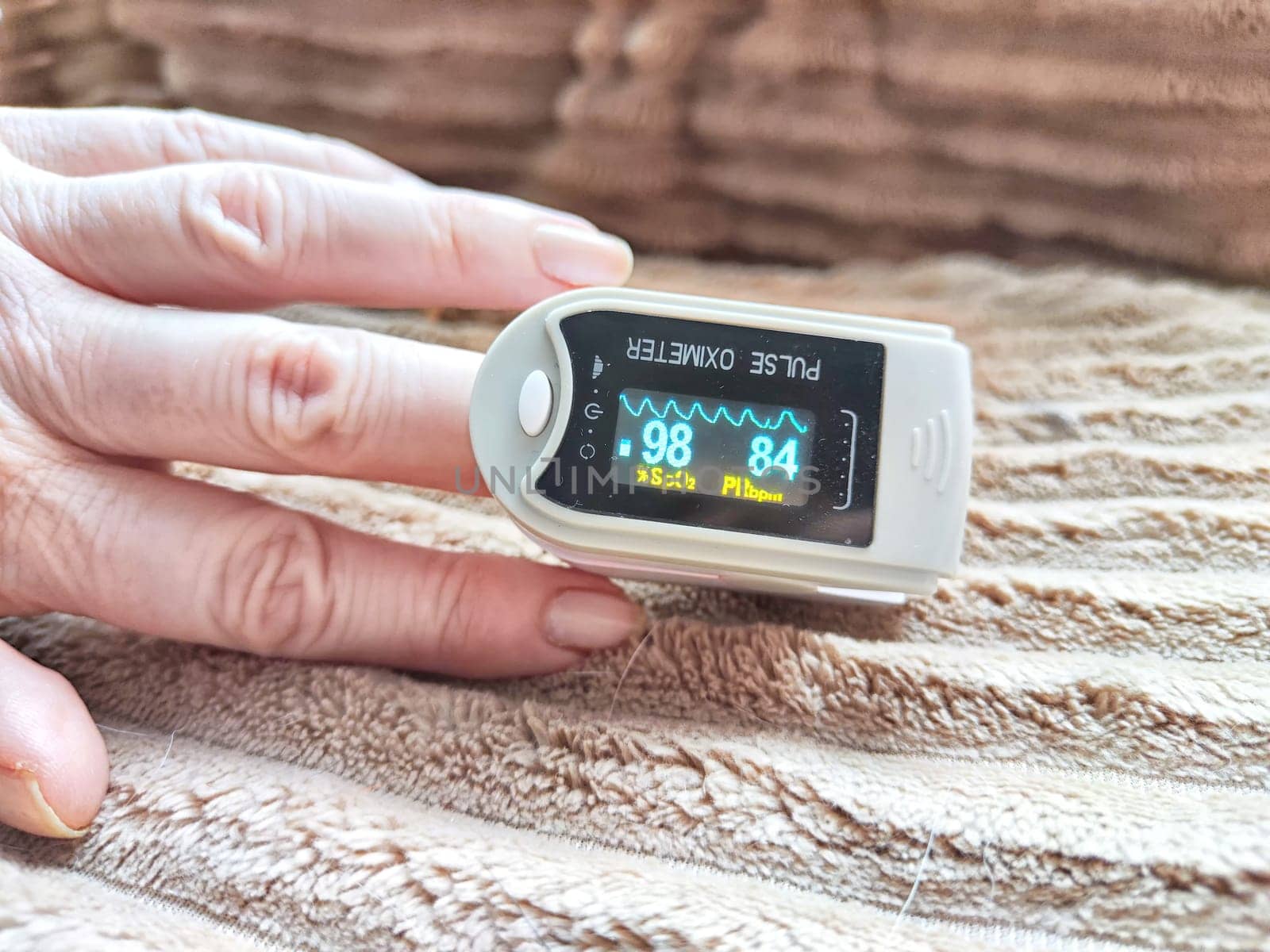 Close up of hand with a pulse oximeter on the finger.
