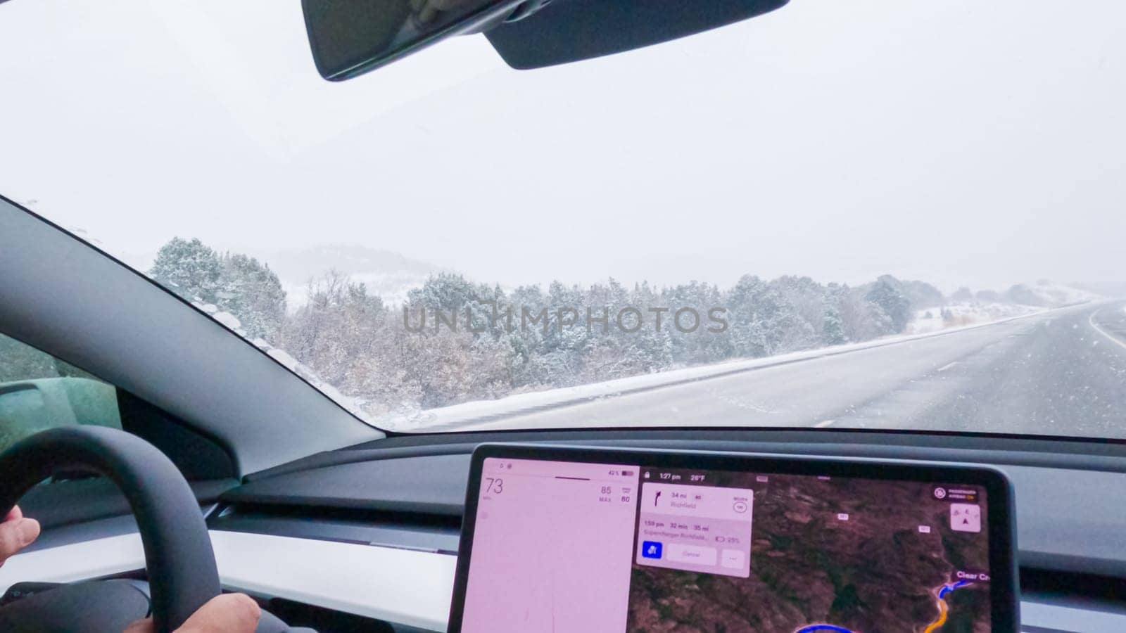 Denver, Colorado, USA-December 7, 2022--POV-In a Tesla electric car, a driver adeptly navigates through Western Colorado's snowy landscapes during a winter storm.