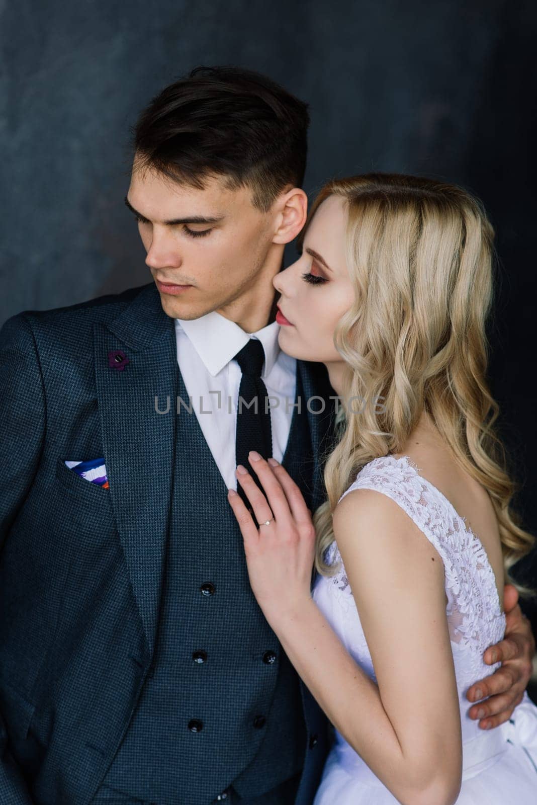 Cute wedding couple in the interior of a classic studio. They kiss and hug each other.