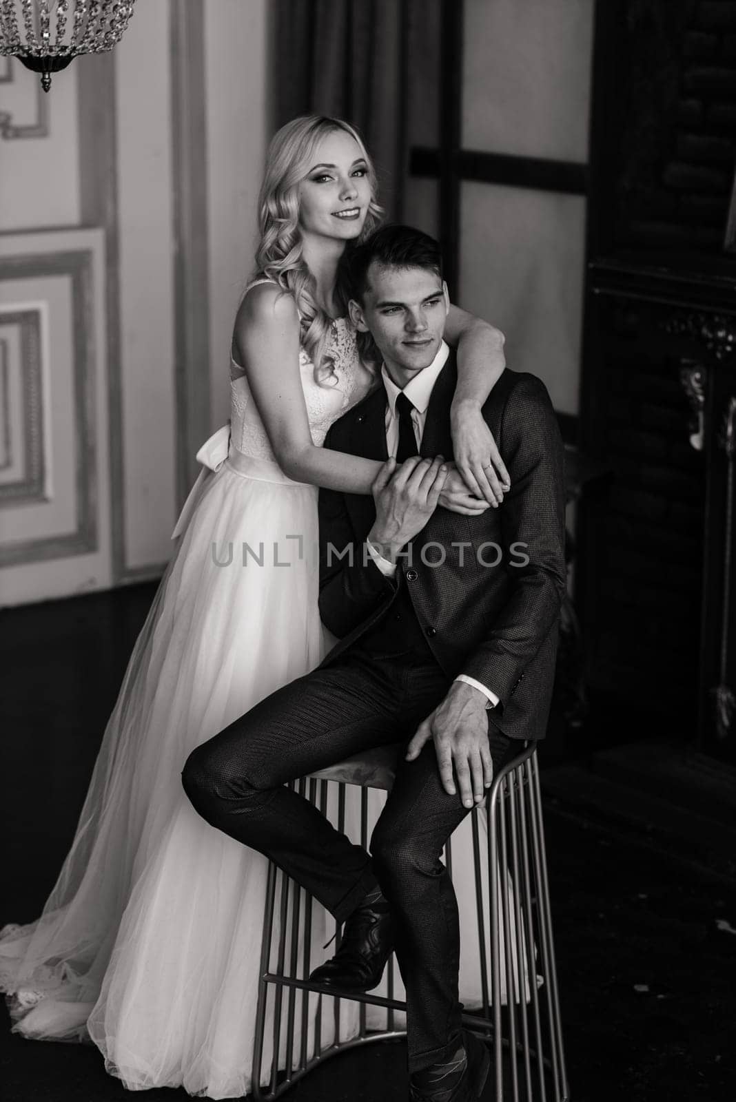 Cute wedding couple in the interior of a classic studio decorated. They kiss and hug each other. by Zelenin
