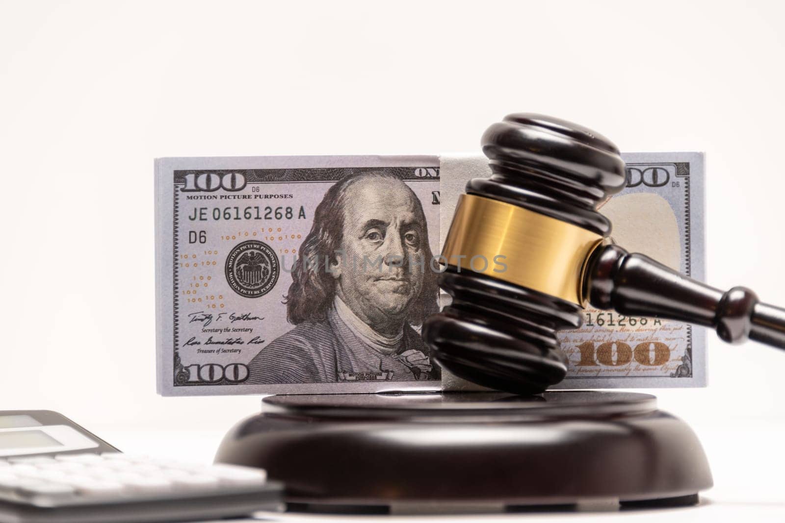 An isolated image of a judge's gavel on a stack of cash with a calculator, signifying legal fines or bail