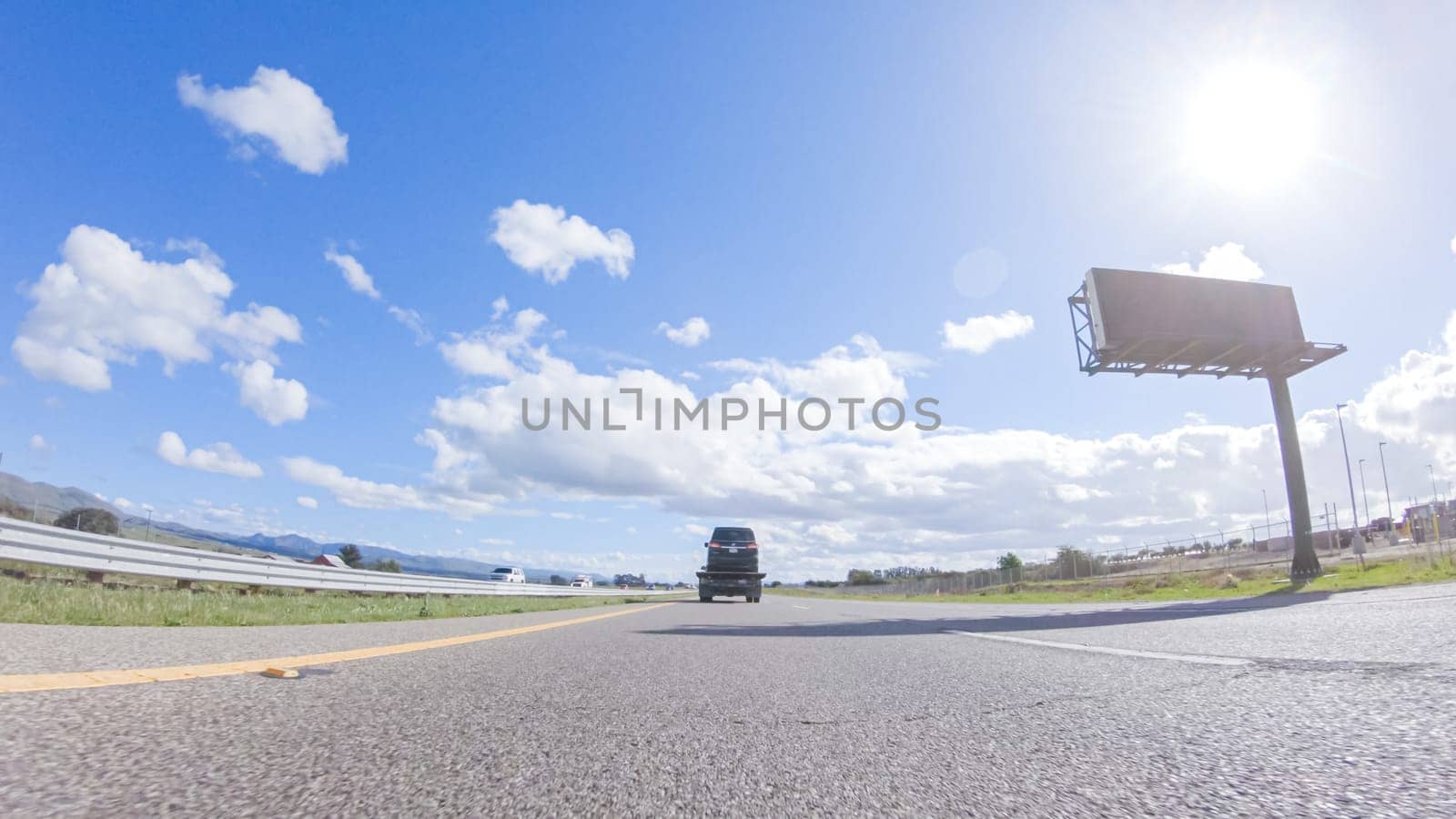 On a clear winter day, a car smoothly travels along Highway 101 near Santa Maria, California, under a brilliant blue sky, surrounded by a blend of greenery and golden hues.