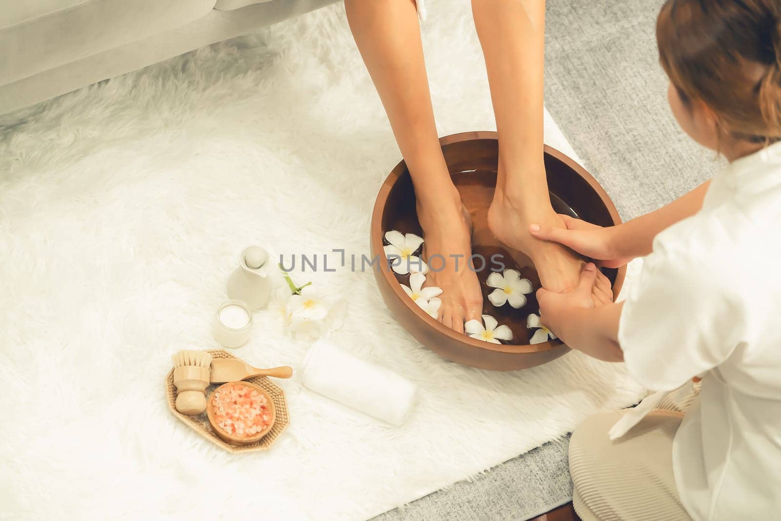 Woman indulges in blissful foot massage at luxurious spa salon while masseur give reflexology therapy in gentle day light ambiance resort or hotel foot spa. Quiescent