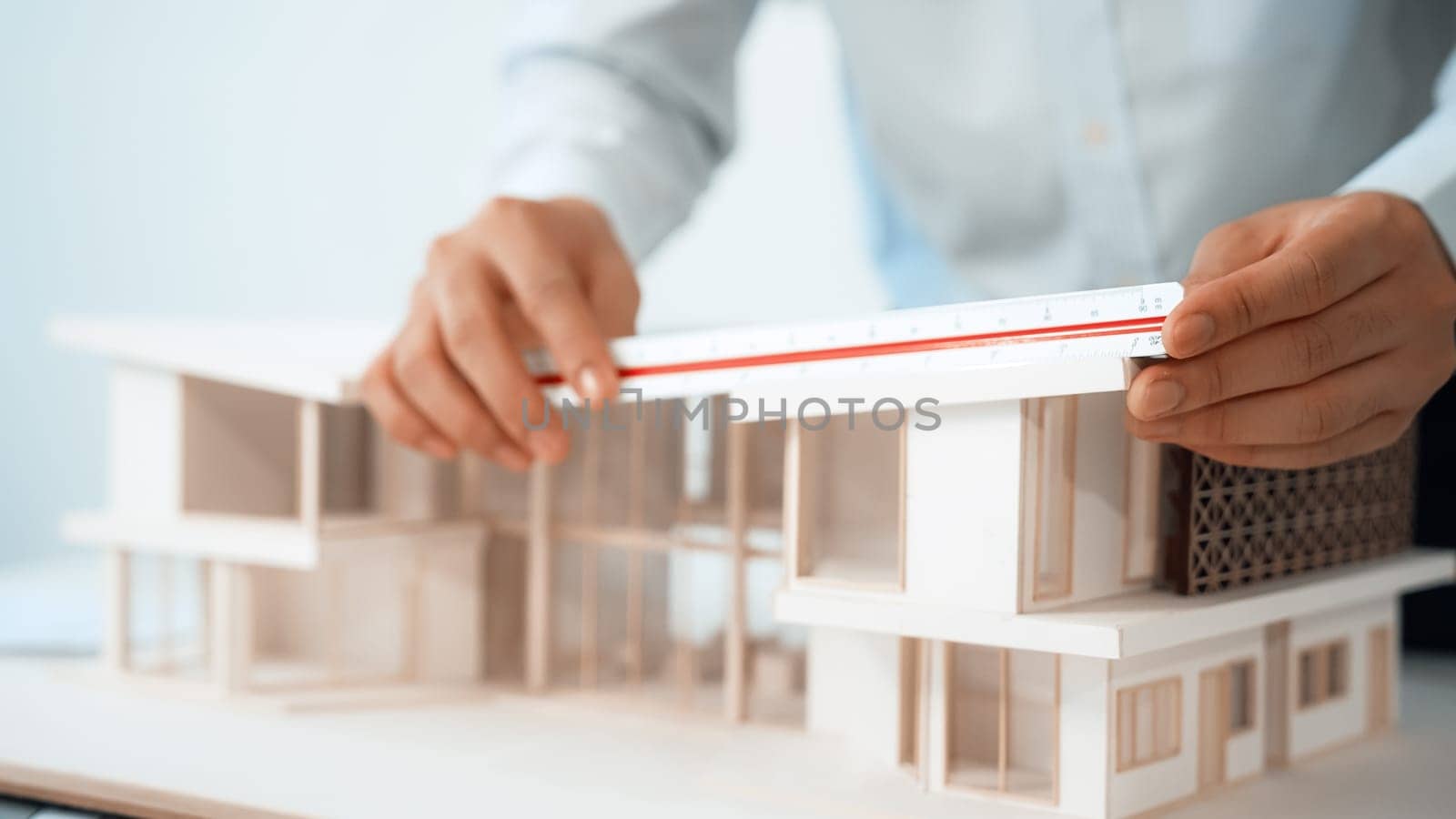 Closeup of professional engineer uses ruler to measure house model. Immaculate by biancoblue