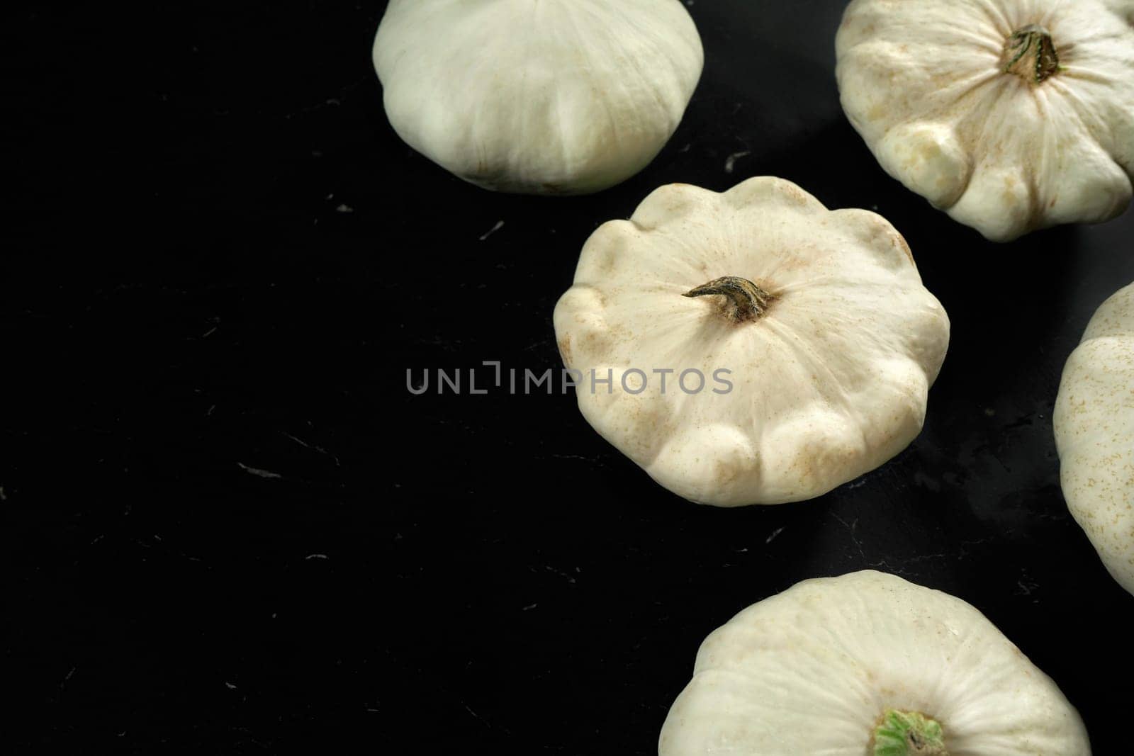 White pattypan squash pumpkins on black stone like board, space for text left side by Ivanko
