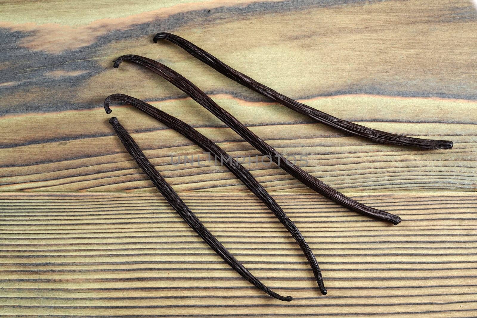 Four vanilla beans on wooden board, view from above by Ivanko