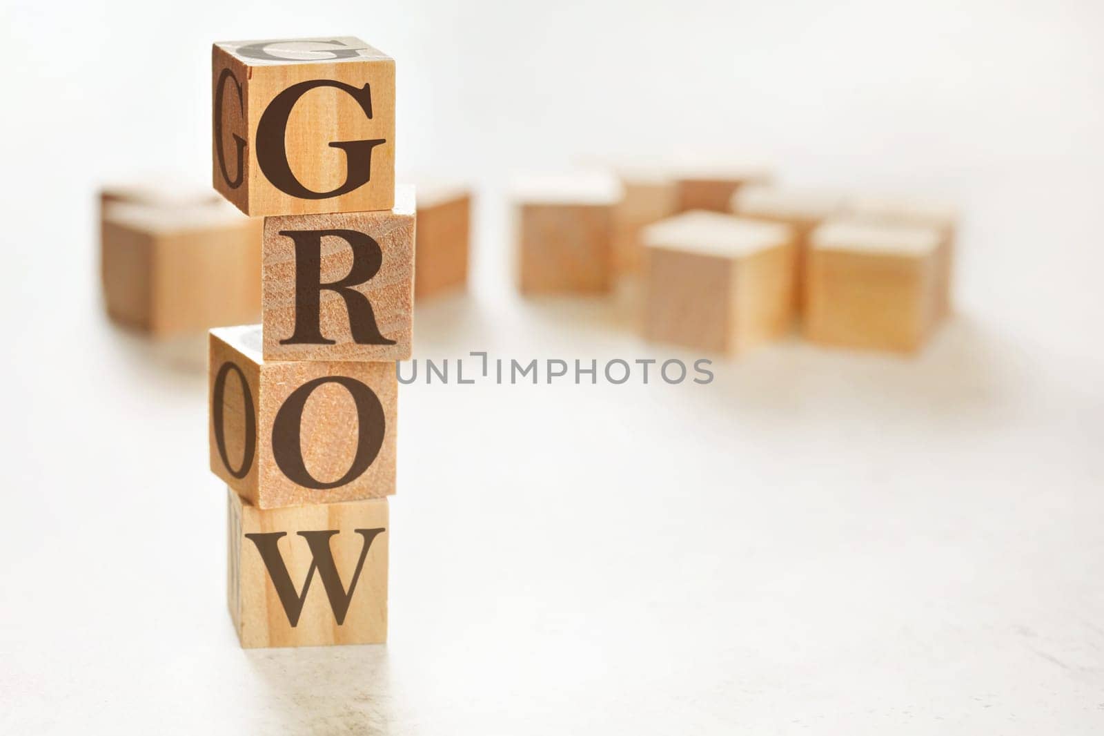 Four wooden cubes arranged in stack with text GROW on them, space for text / image at down right corner by Ivanko
