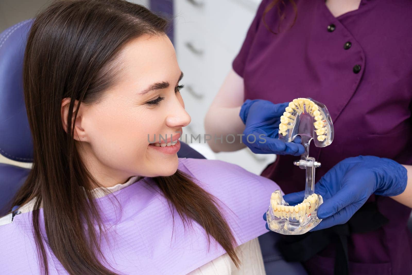 Dentist explains the procedure of alignment of teeth to the patient using a jaw layout in modern dentistry clinic