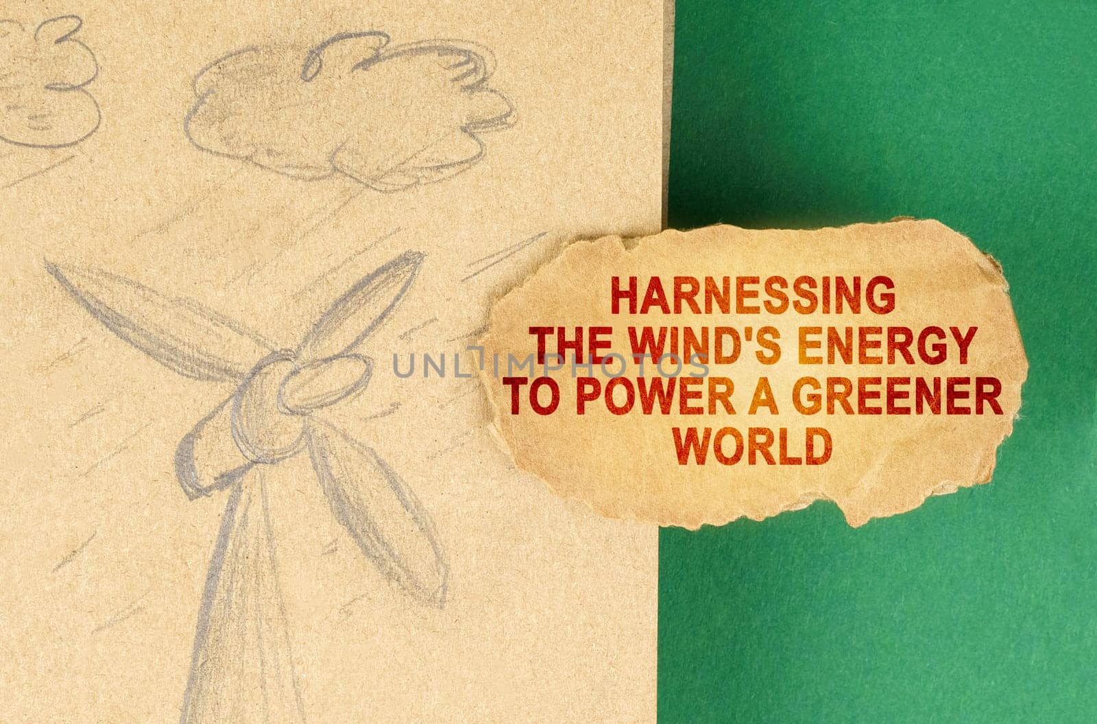 Alternative energy concept. On a green surface there is a drawing with a wind generator and a cardboard with the inscription - Harnessing the wind's energy to power a greener world