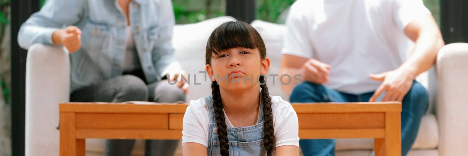 Stressed and unhappy young girl crying and trapped in middle of tension by her parent argument in living room. Unhealthy domestic lifestyle and traumatic childhood depression. Panorama Synchronos